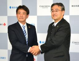 　コンコルディアＦＧの大矢恭好社長（右）の後任に決まり、握手する片岡達也氏＝２２日午後、横浜市