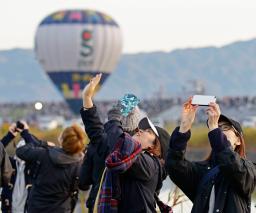 　３年ぶりに有観客で開催された「佐賀インターナショナルバルーンフェスタ」で、飛び立った熱気球に手を振る人たち＝２日午前、佐賀市