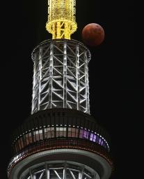 　東京スカイツリー上空に浮かぶ皆既食の状態の月＝８日午後７時２０分、東京都墨田区