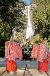 　熊野那智大社の「紅葉祭」で、モミジの枝を手に那智の滝前で神楽を披露する巫女＝１４日午前、和歌山県那智勝浦町