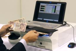 　レジ用機器で新紙幣の読み取り試験をする様子＝２１日、東京都北区の国立印刷局東京工場