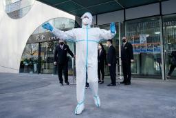 　新型コロナ対策で封鎖されたオフィスビルの前に立つ防護服姿の担当者＝２１日、北京（共同）