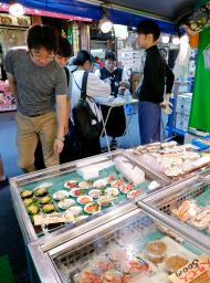 　東京・築地場外市場の鮮魚店で品定めをする買い物客＝２５日午前