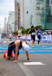 　北海道マラソンでゴール後に倒れ込むランナー＝２７日午前、札幌市