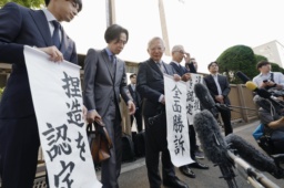 　大川原化工機訴訟の東京高裁判決を受け、「全面勝訴」と書かれた紙を手にする大川原正明社長ら＝２８日午後、東京高裁前