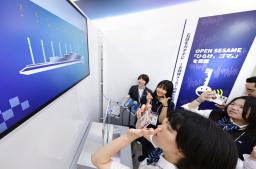 　大阪ヘルスケアパビリオンで、大阪弁の発音をＡＩが判定するシステム「ｋｅｙ　ｖｏｉｃｅ〜開けゴマの世界〜」に挑戦する来場者＝２９日午前、大阪市此花区の夢洲