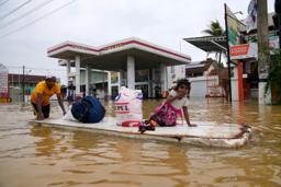　２９日、スリランカ・コロンボで、冠水した道路を進む人たち（ＡＰ＝共同）