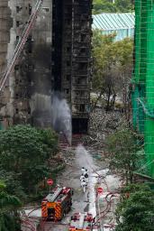 　大規模火災が起きた香港北部の高層住宅に入る捜索隊員ら＝３０日、香港北部・新界地区大埔（共同）