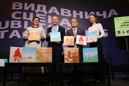 　式典で、日本からウクライナに寄贈された絵本を手にする出版社「ラーノク」のビクトル・クルフロフ社長（左から２人目）ら＝５月３１日、キーウ（共同）