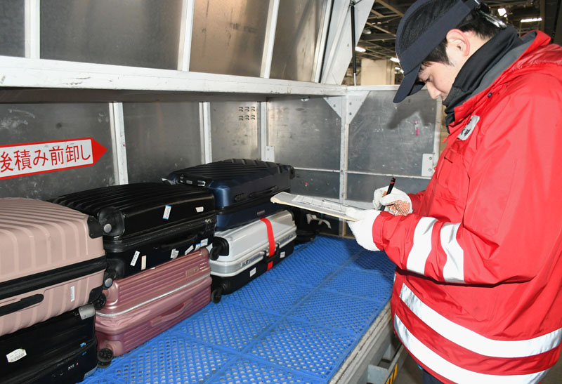 手荷物を正しい送り先に届けるため確認作業をする谷奥さん=成田市