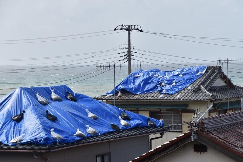 被災した住宅の屋根を覆うブルーシート＝２３日午後１時２０分ごろ、館山市布良