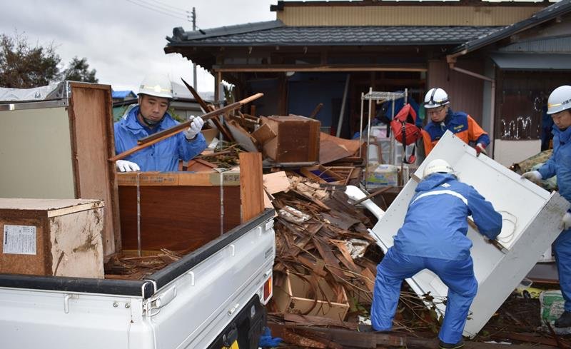 被災した住宅から壊れた家財道具などを運び出す消防団員＝２２日午後２時ごろ、市原市下野
