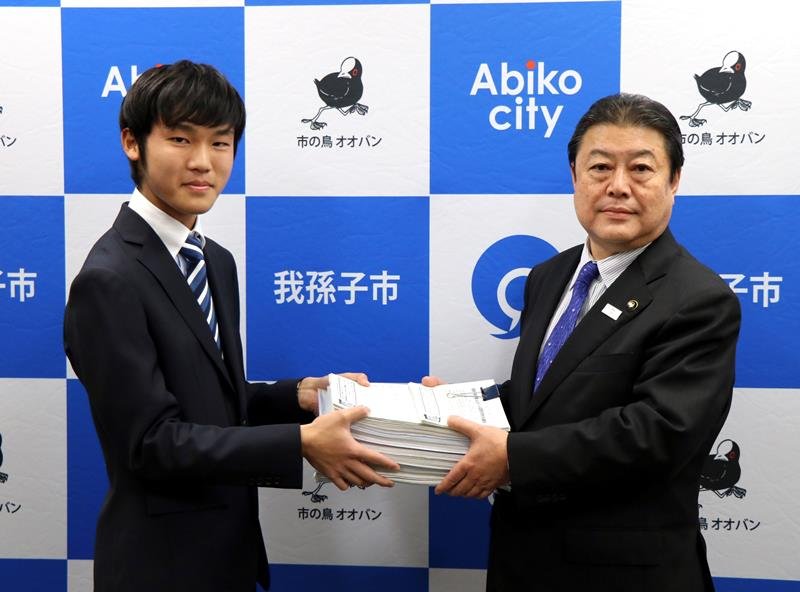 発車メロディーの変更を求める署名を星野市長に提出する織田さん（左）＝我孫子市
