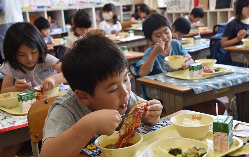 大きな房州エビ（伊勢エビ）を頬張る児童＝南房総市立富山小