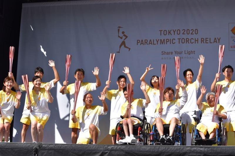 聖火をつなぎ、笑顔で手を振る参加者たち＝１８日、千葉市中央区の千葉ポートタワー前広場