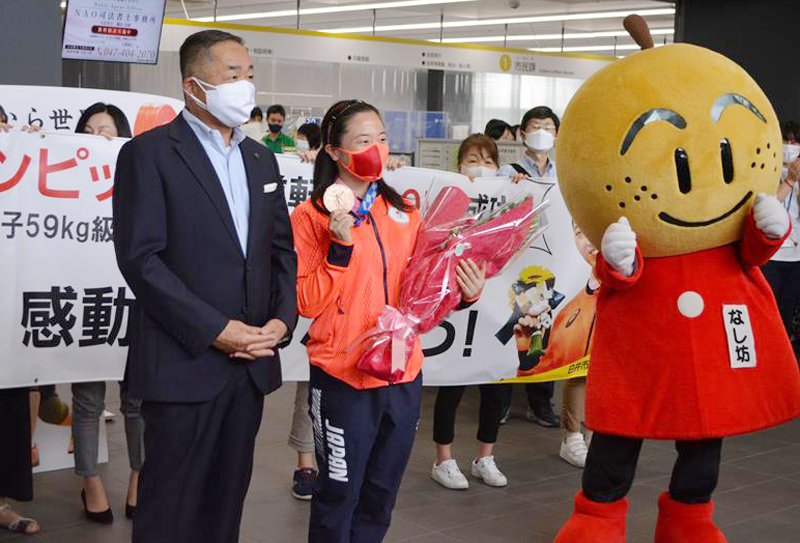 地元の白井市役所で笠井市長（前列左）らの出迎えを受け、五輪重量挙げの銅メダルを披露する安藤選手＝２４日