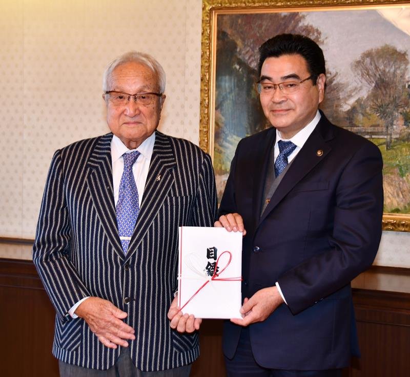 寄付の目録を鈴木有市長（右）に手渡した根本さん＝野田市
