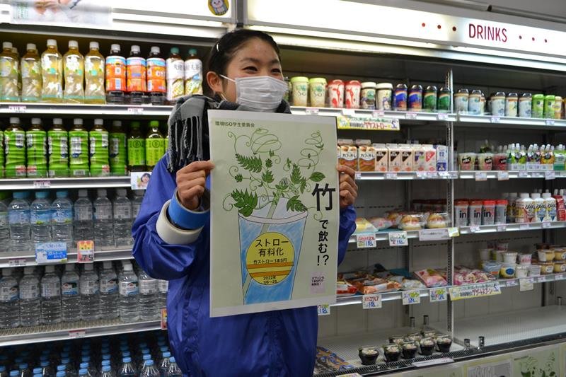 売店の飲料コーナーの前で、環境ＩＳＯ学生委員会の委員がポスターを手に竹製ストローの導入をＰＲした＝６日、千葉市稲毛区の千葉大学西千葉キャンパス