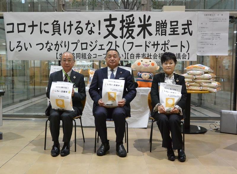 寄贈を受けた米を持つ（左から）コープみらいの永井伸二郎副理事長、笠井市長、松本会長＝白井市保健福祉センター
