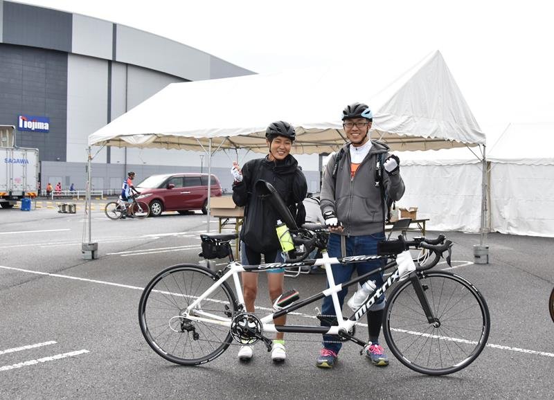 ２人乗り自転車を前にガッツポーズをする鹿沼さん（左）と荒巻さん＝木更津市
