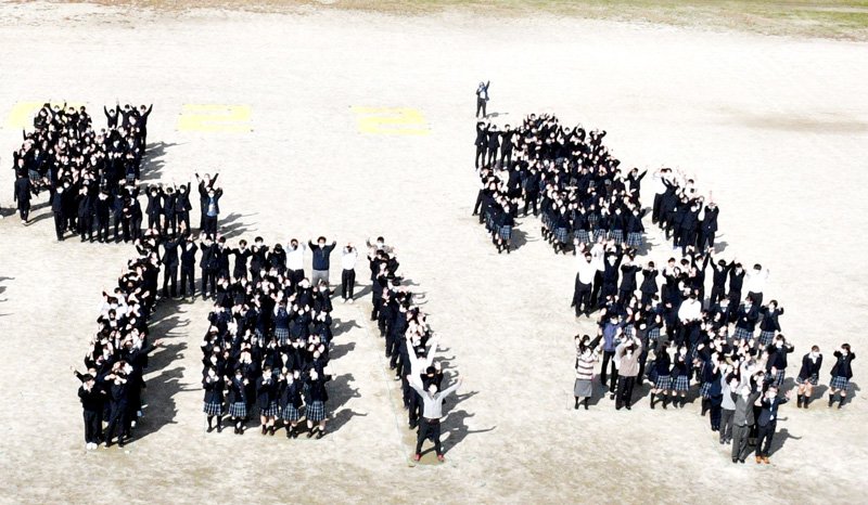 学校創立１００周年を記念し、校庭で生徒らが人文字をつくり、ドローンで空撮した＝香取市