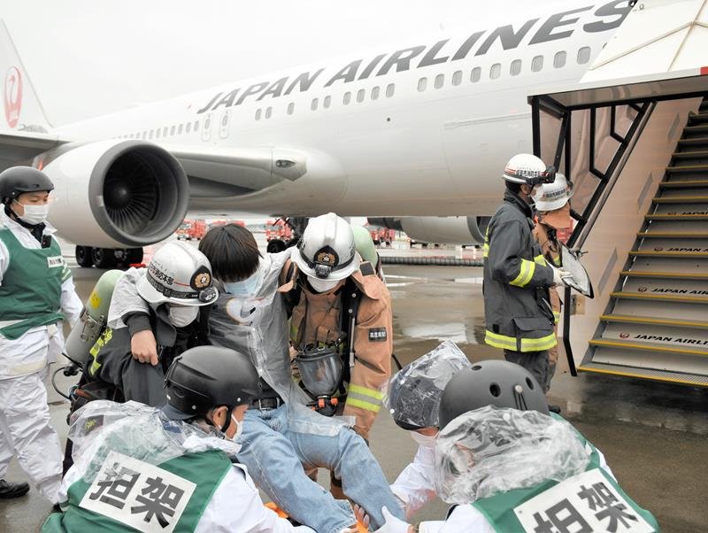 けがを負った搭乗客を航空機から運び出す訓練をする消防隊員ら＝１３日、成田空港