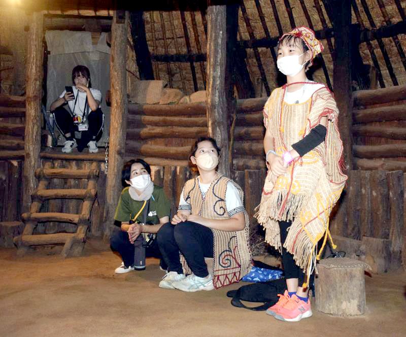 竪穴住居の中で学芸員に質問する児童