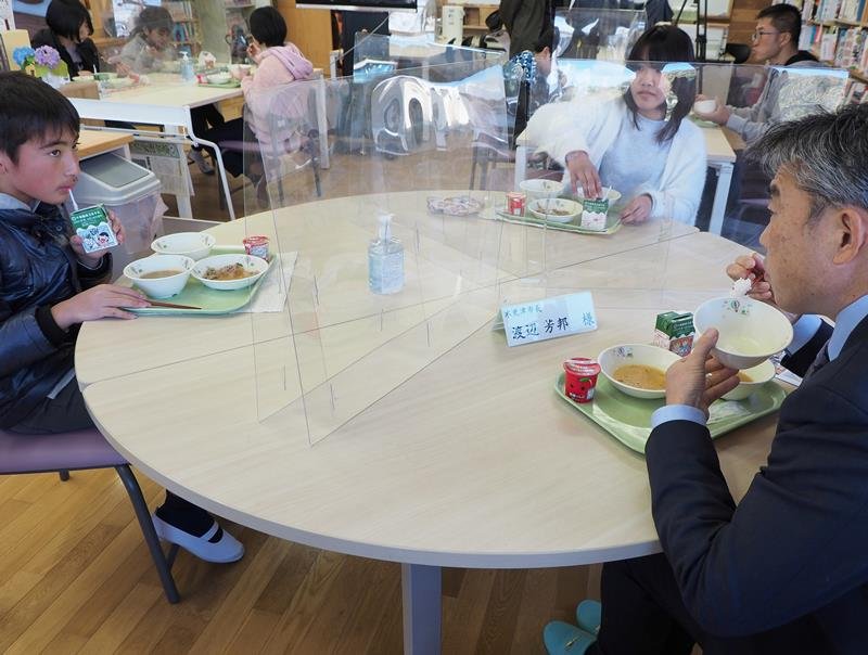 地元産豚肉を使った特別メニューの給食を渡辺市長（右）と一緒に食べる子どもたち＝木更津市
