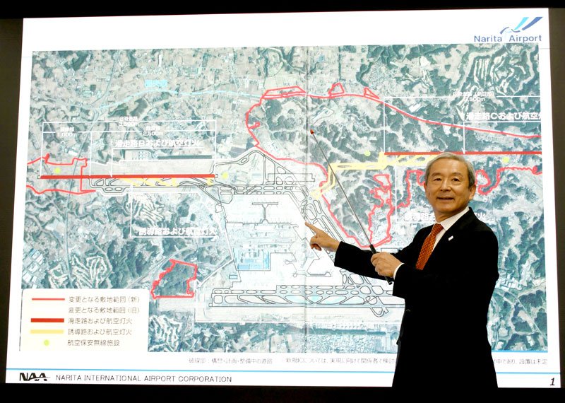 成田空港のマップを指さして中間取りまとめ案について説明する田村社長。上が貨物地区、下が新ターミナルの建設を検討するエリア＝１４日、東京都