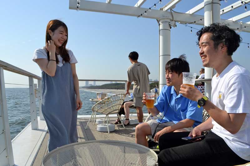海辺でビールを飲みながら涼む若者ら＝１８日午後３時半ごろ、千葉市美浜区の稲毛海浜公園