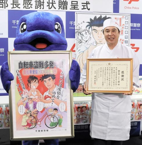 感謝状を手にするさとうさん。ポスターは自転車の二重施錠を呼びかけている＝千葉市中央区の県警本部
