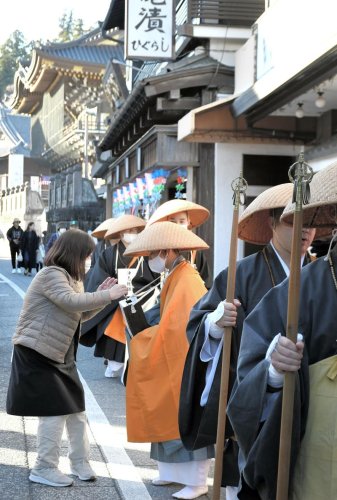 成田山新勝寺の総門近くで店員から浄財を託される僧侶＝成田市
