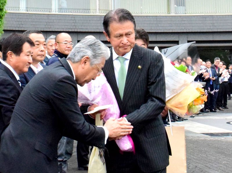 ともに退任する豊田副市長（手前）と握手をして市役所を去る田中市長＝２０日、茂原市