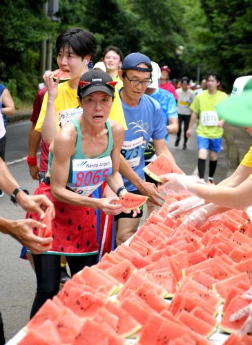 レース終盤の地点に設けられた給スイカ所でスイカを受け取るランナー＝１６日、富里市