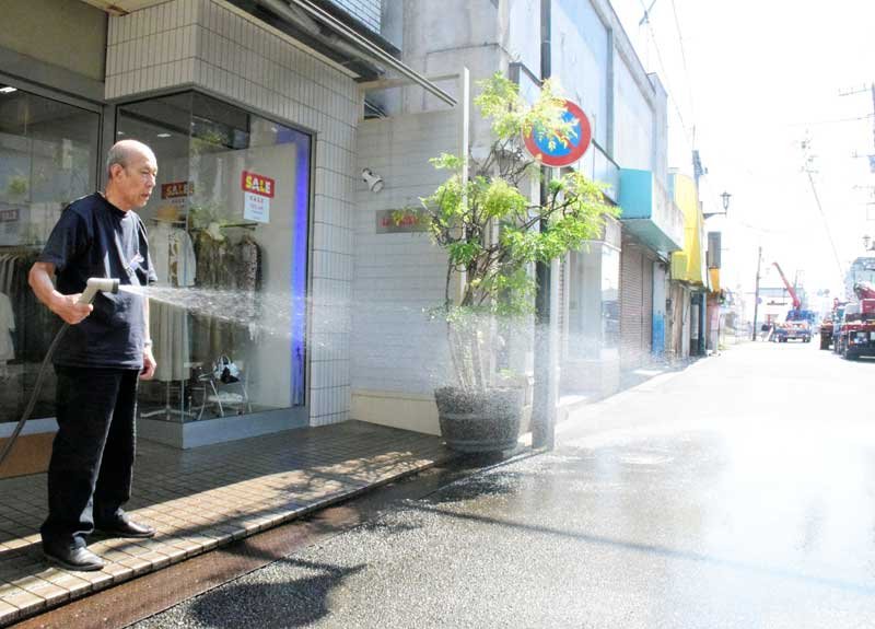 気温３５度以上の猛暑日になった茂原市では、店先に水をまく人の姿が＝２２日午後２時１５分ごろ
