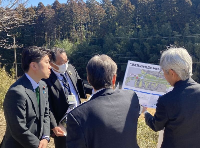 成田空港のＣ滑走路の新設予定用地でＮＡＡ職員から計画について説明を受ける中野国交相（左）＝２４日、芝山町