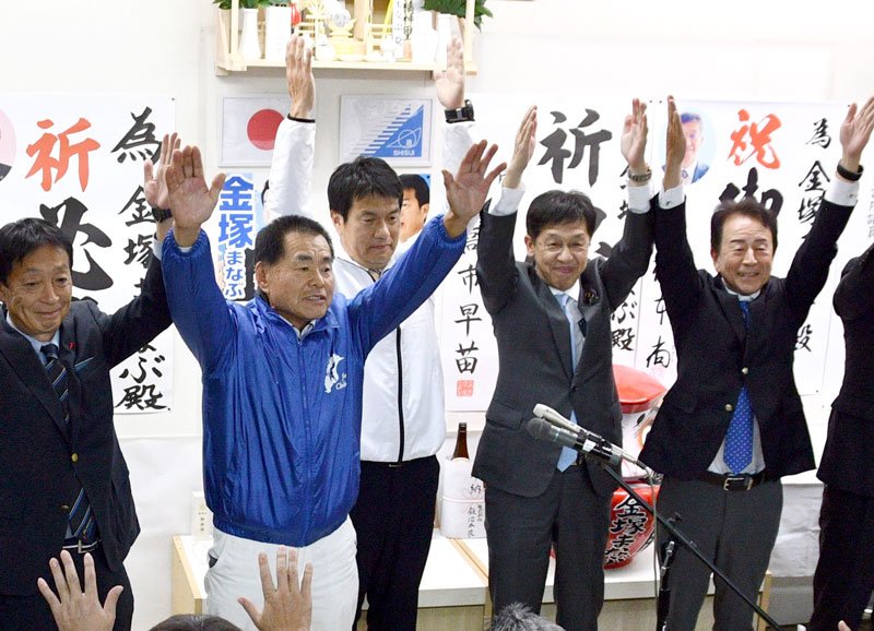 初当選を決め、万歳する金塚氏（左から３人目）。松本デジタル相（同４人目）も祝福した＝３０日午後１０時半ごろ、酒々井町