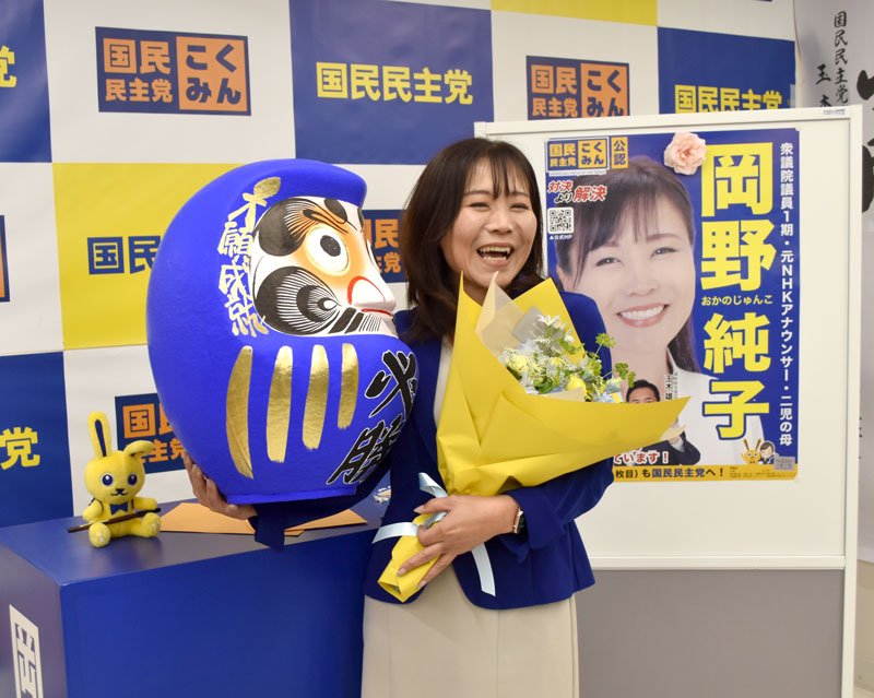 再選を決め、必勝だるまと花束を手に笑顔を見せる国民民主党の岡野氏＝９日、市川市

