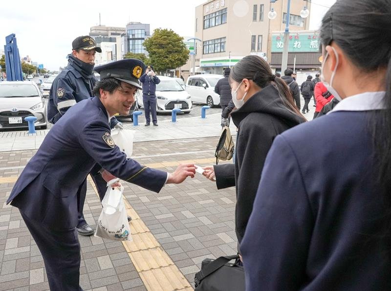 ＪＲ銚子駅で受験生に啓発物を手渡す銚子署員＝１７日、銚子市
