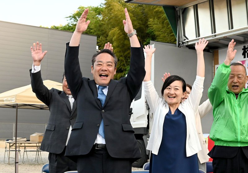 無投票で再選を決め、支持者らと万歳三唱する橋本氏（前列左）＝１２日、栄町