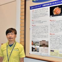 ヨウサイイソギンチャクの解説パネルと柳研究員＝勝浦市の海の博物館
