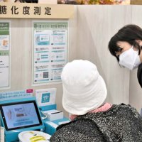 買い物客を対象とした健康測定コーナーで、生活習慣改善に向けた助言を行うスタッフ