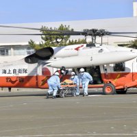 訓練で、海自の救難ヘリコプターから要救助者を引き継ぐ救急隊員ら＝５日、館山市の北条小学校