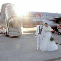 「空の上の結婚式」を前に、チャーター便の前で記念撮影＝成田空港
