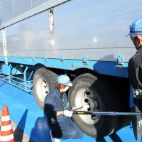 脱落防止のために大型車のホイールとナットがしっかりと締め付けられているか確認する整備士
