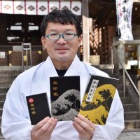 御朱印巡りに必要な神社案内帳と、オリジナルの御朱印帳を掲げる岡野さん＝鴨川市
