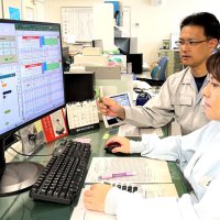 独自システムで社内の稼働状況を確認する元木代表（右から２人目）
