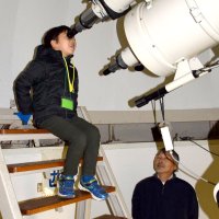 天体望遠鏡で月を観察する児童と講師を務めた田辺さん＝睦沢町立中央公民館