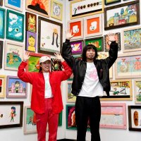 絵本原画の前でポーズを取る阿部（右）と吉岡