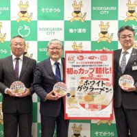 カップ麺化されたホワイトガウラーメンをアピールする粕谷智浩市長（右から２人目）と斎藤昭生・千葉薬品社長（同３人目）ら＝袖ケ浦市
